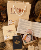 The Handmade charms branded packaging with a money magnet bracelet, book, and card on a rustic background