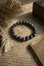 Bloodstone bracelet on an old book with dried flowers and a wooden box.